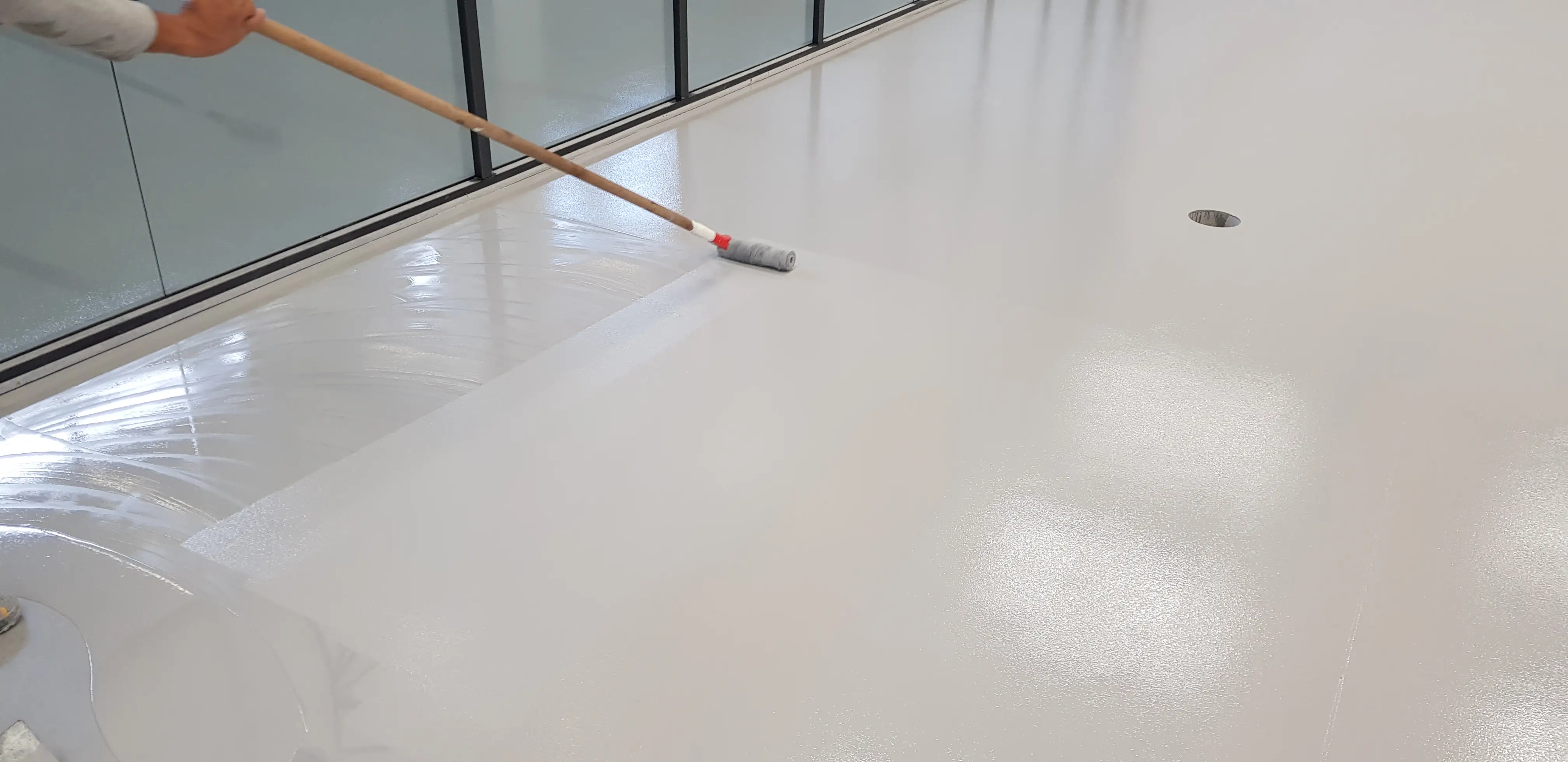 Corredor industrial recebendo pintura epóxi azul com faixas brancas para demarcação de segurança.