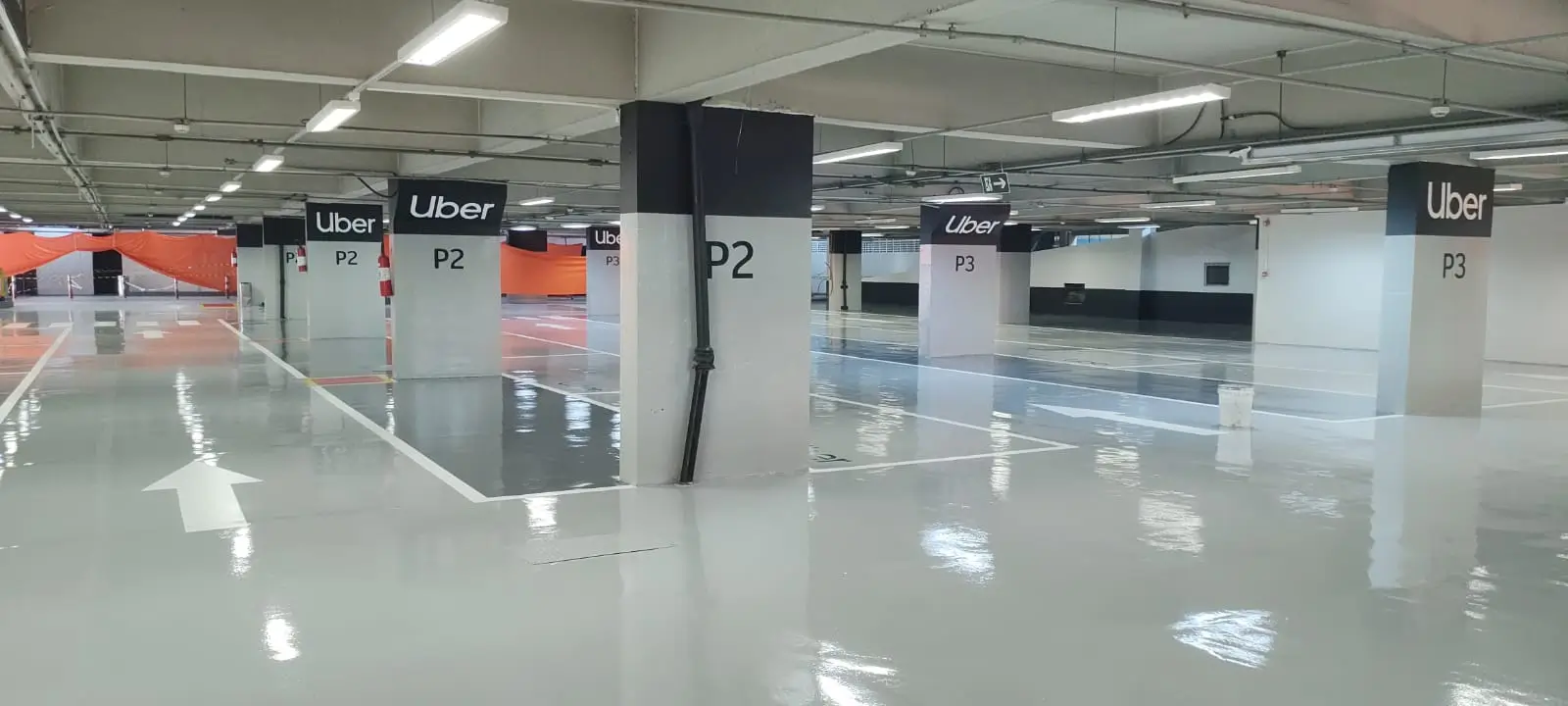 Estacionamento com piso epóxi claro mostrando acabamento uniforme e resistência mecânica.