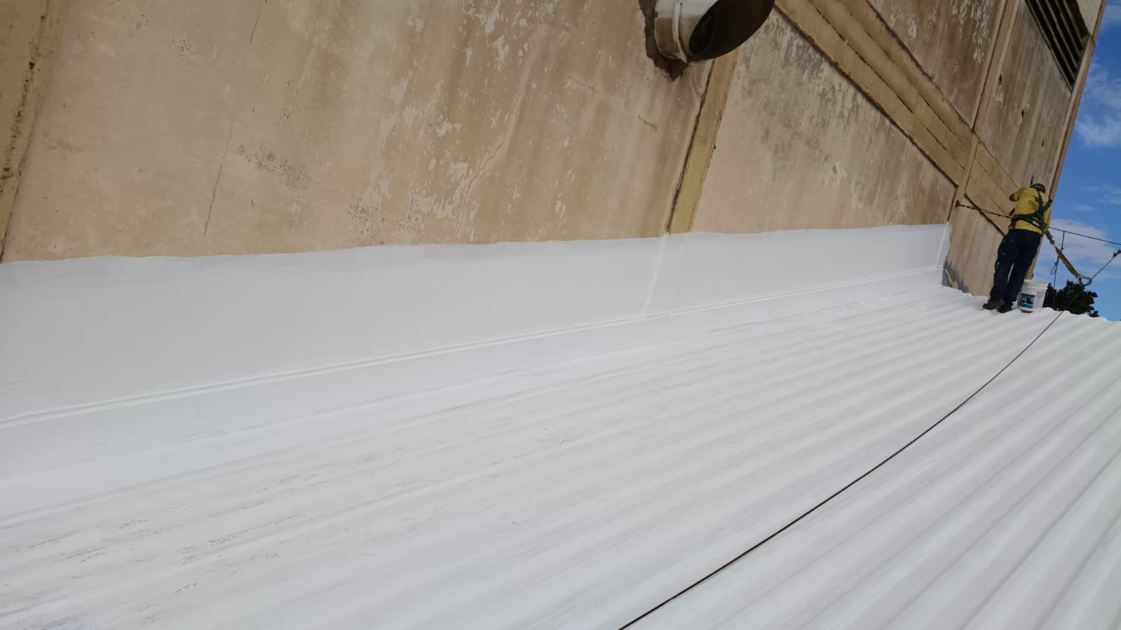 Cobertura metálica industrial com camada de borracha líquida branca refletiva.