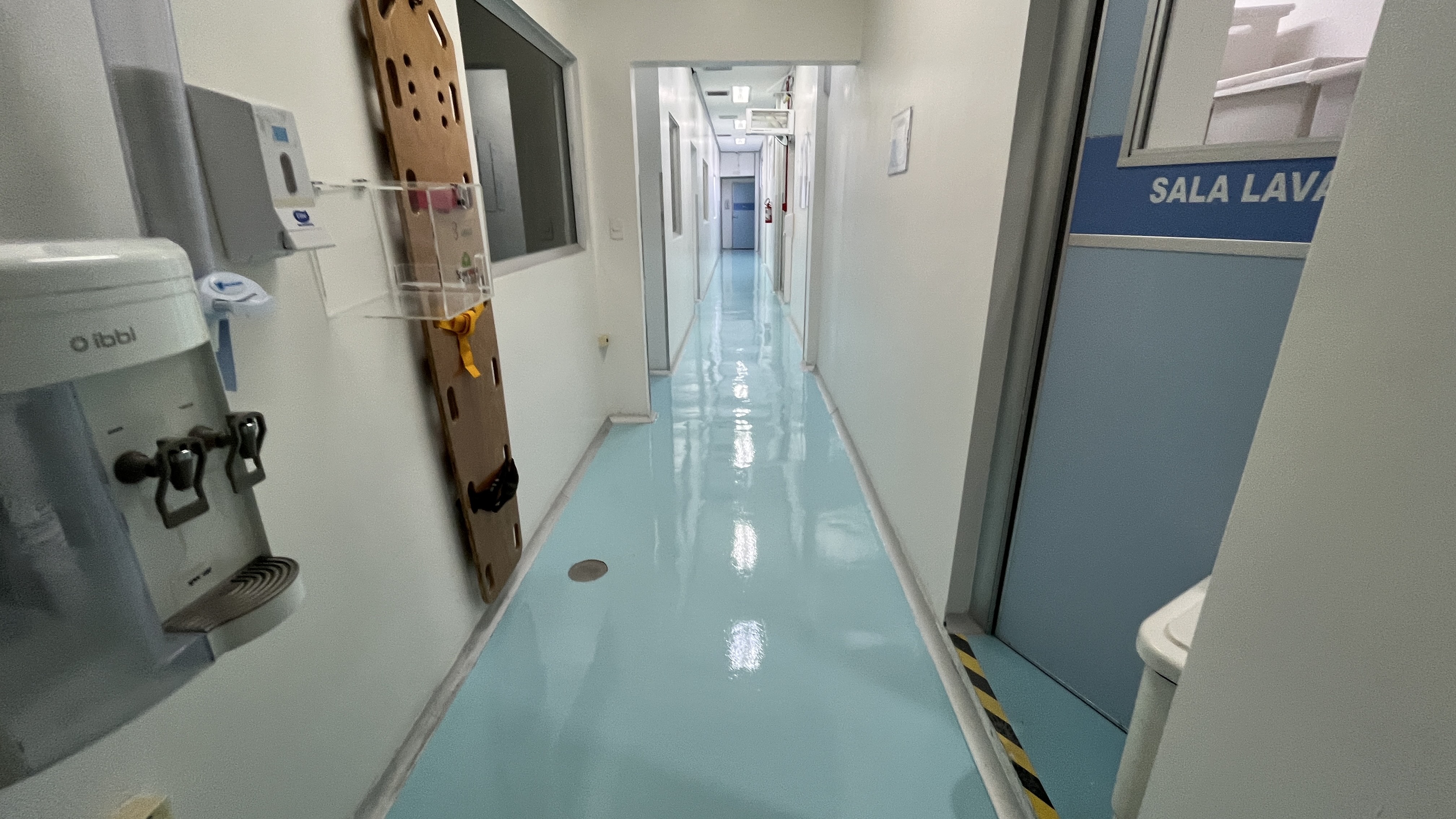 Área técnica de hospital com piso autonivelante concluído, junto a portas e equipamentos de rotina hospitalar.