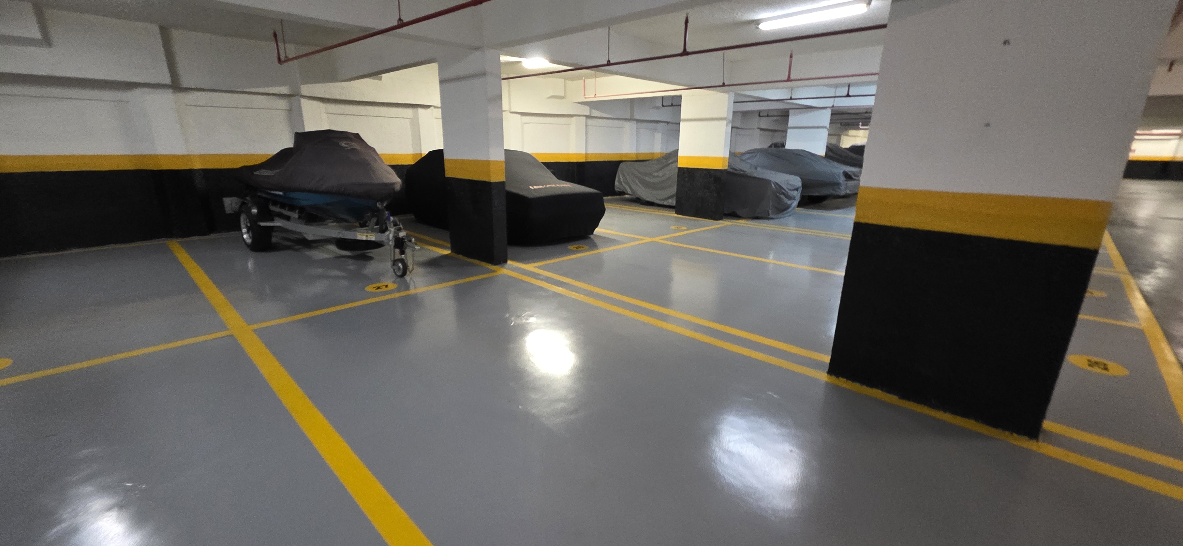 Trecho de garagem com piso epóxi cinza recém-aplicado, acabamento uniforme e brilhante.