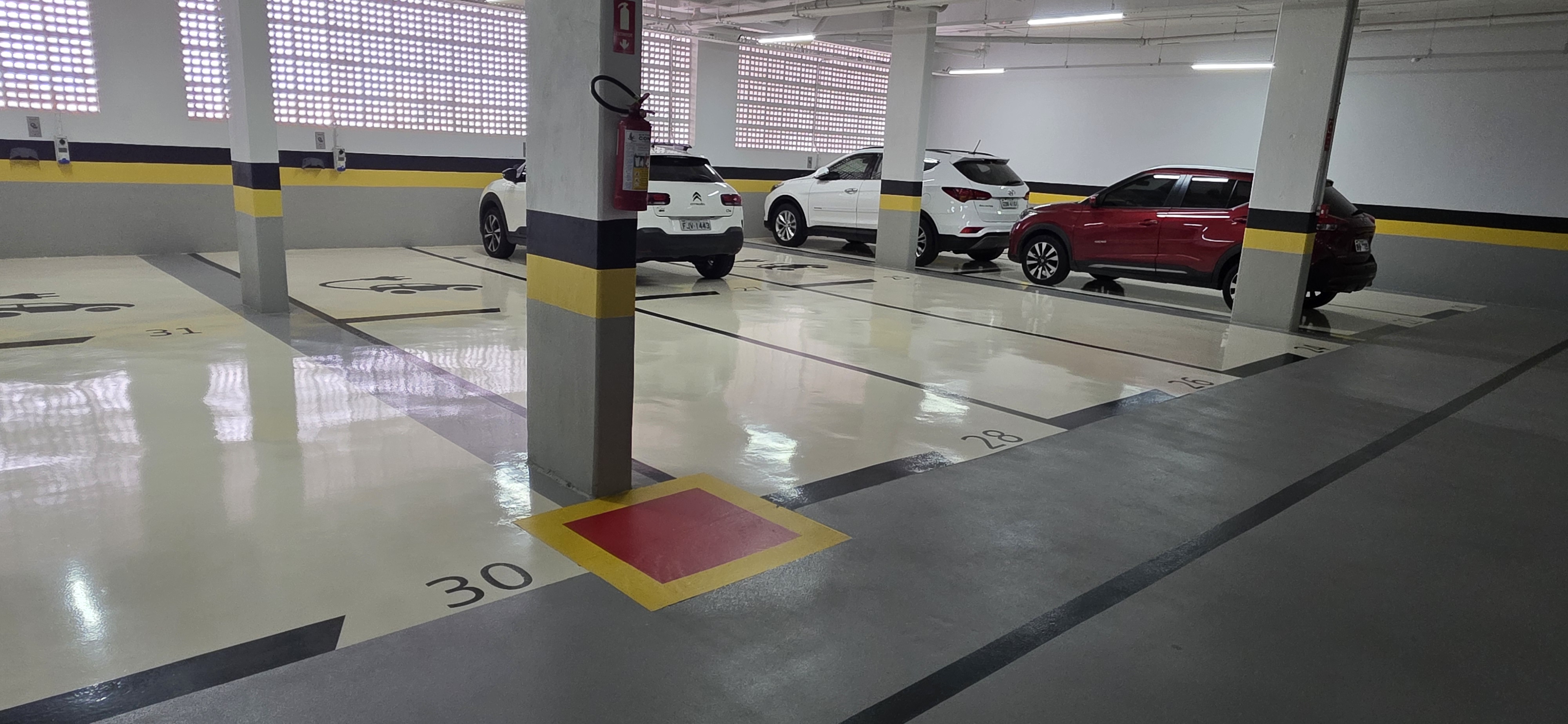 Detalhe de vaga de garagem com piso epóxi cinza e demarcação de numeração.