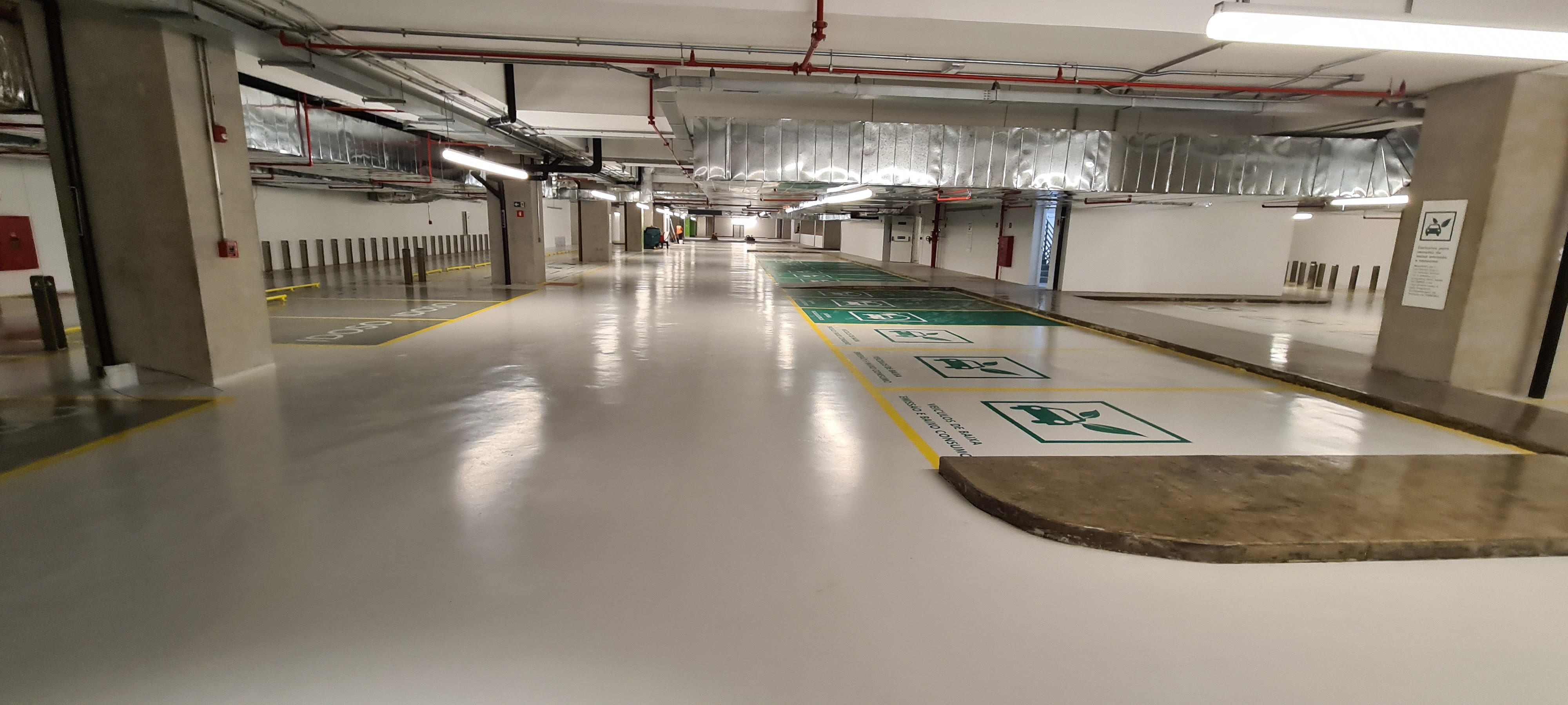 Garagem de condomínio com piso epóxi aplicado, faixas de circulação e colunas sinalizadas.