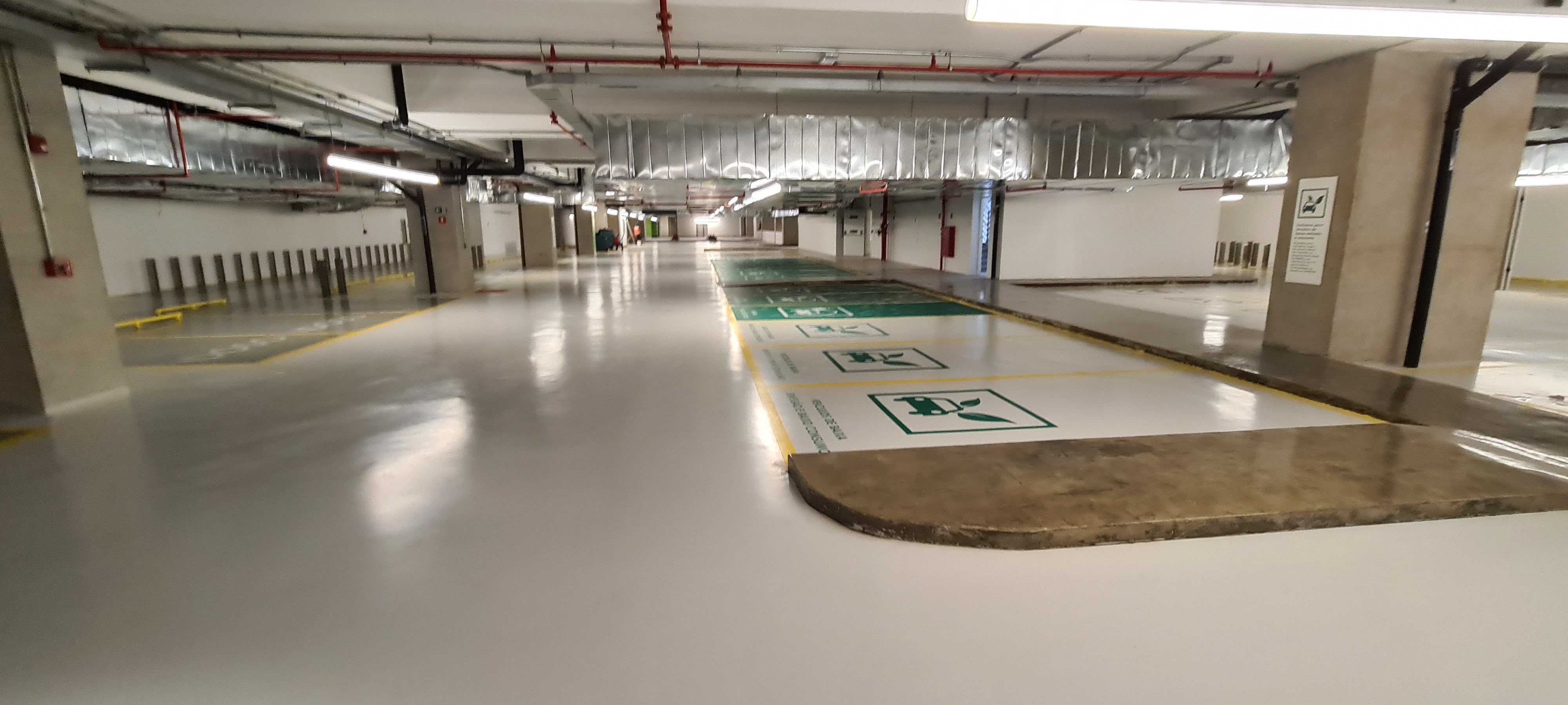 Estacionamento subterrâneo com piso epóxi cinza e faixas de pedestres brancas.