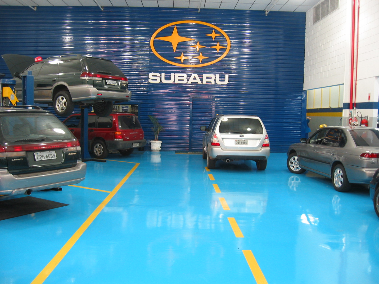 Setor de reparo automotivo com piso epóxi aplicado e faixas de demarcação de segurança.