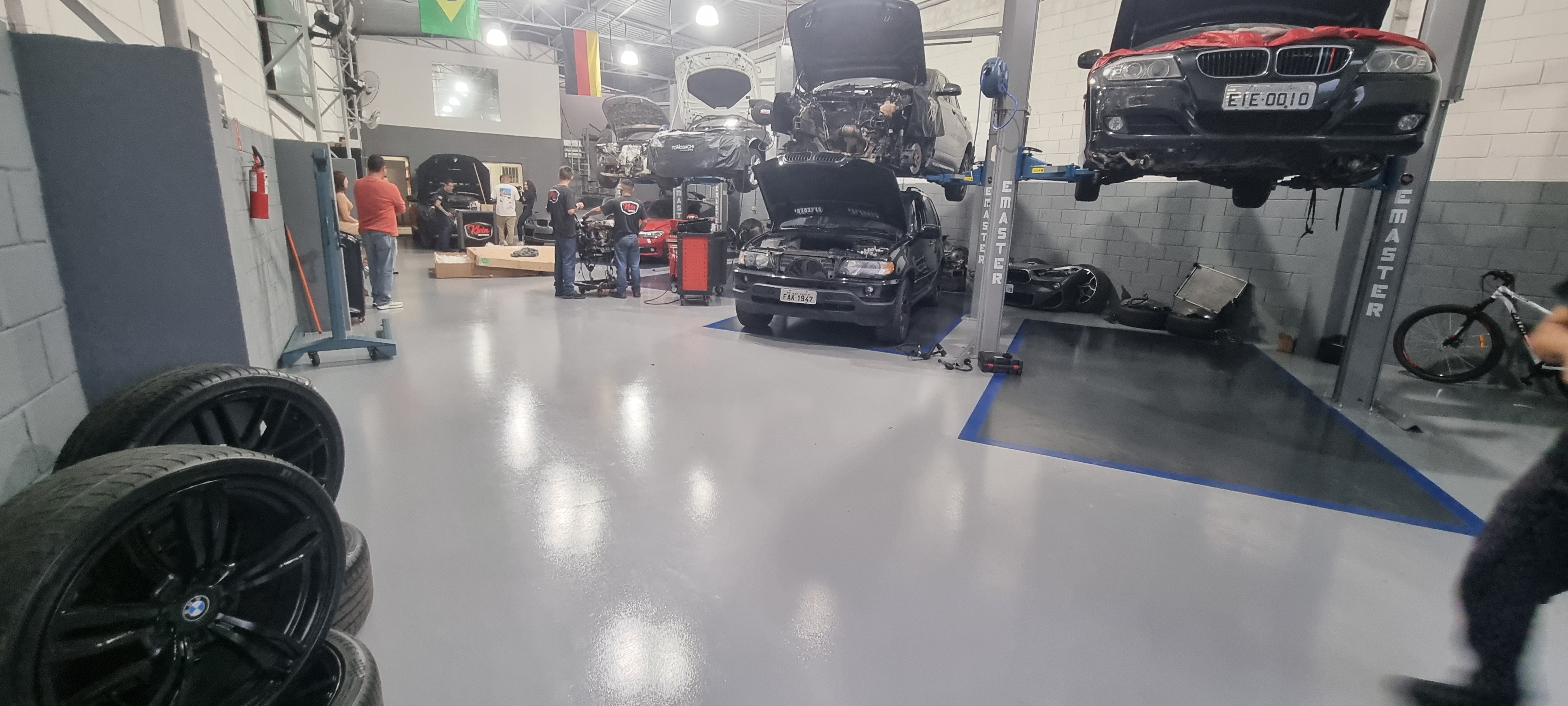 Trecho de oficina com piso epóxi cinza recém-aplicado, elevadores automotivos ao fundo.