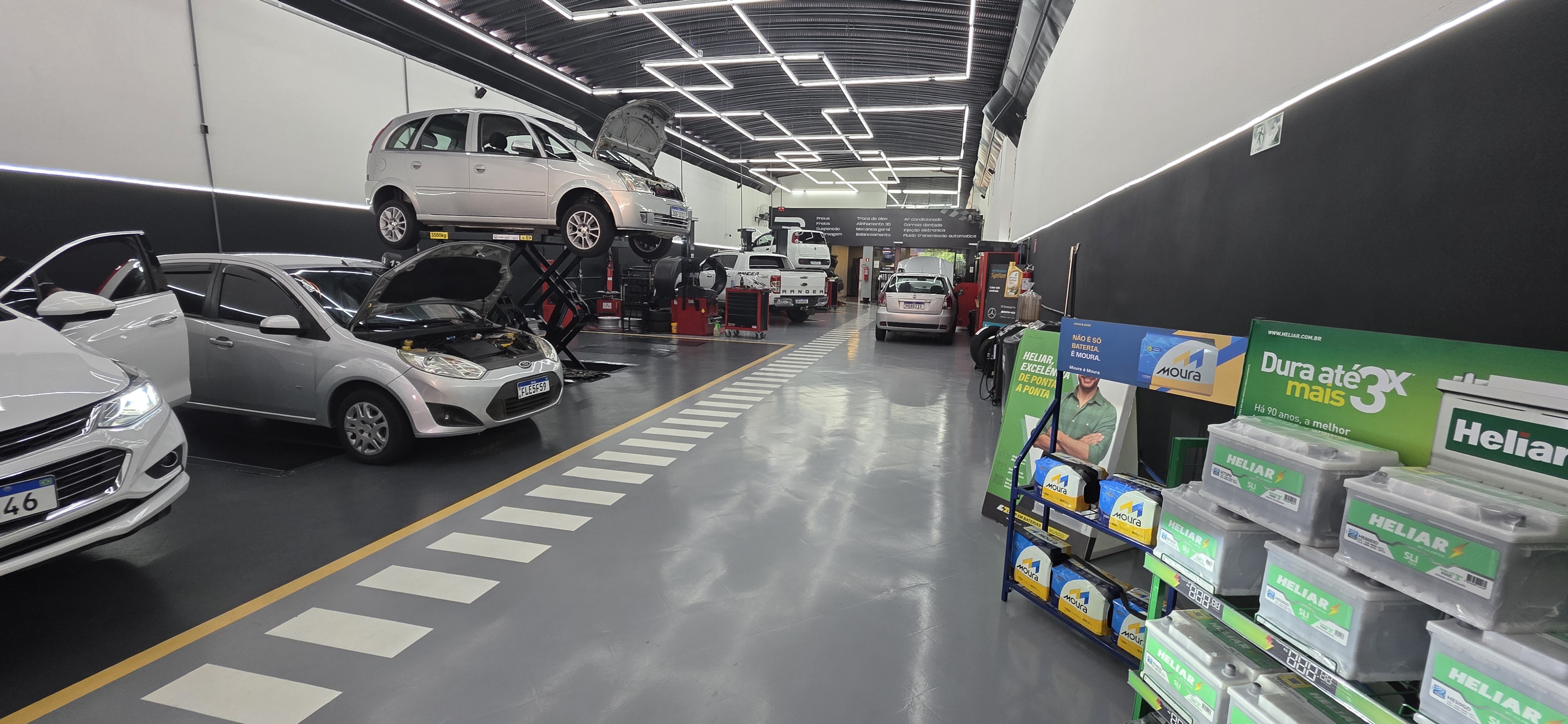 Área de atendimento de concessionária com piso epóxi claro e veículos em exposição.