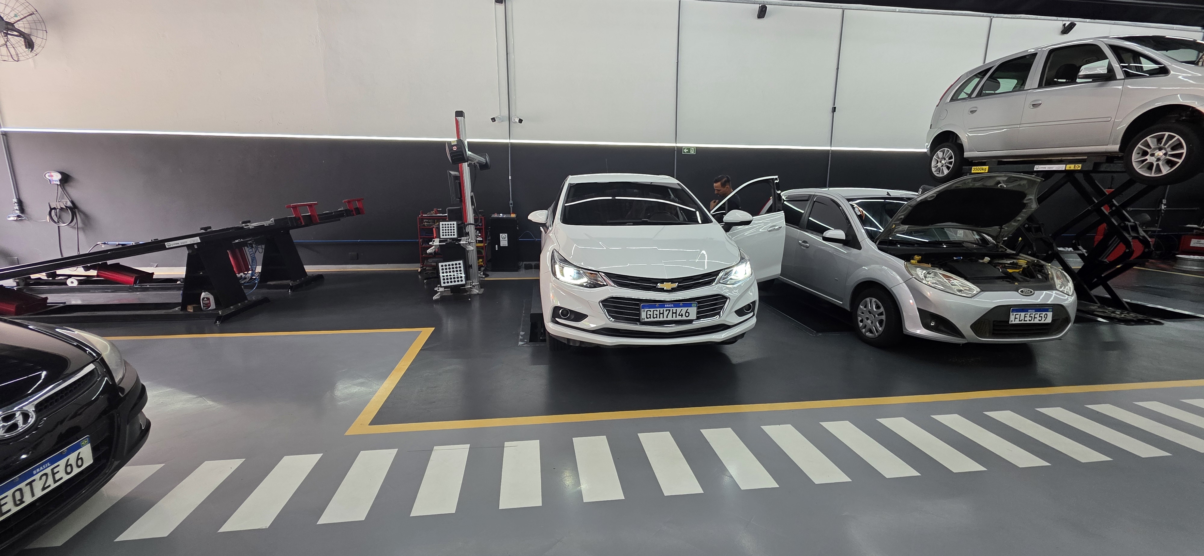 Corredor de oficina mecânica com piso epóxi cinza e demarcações de circulação.