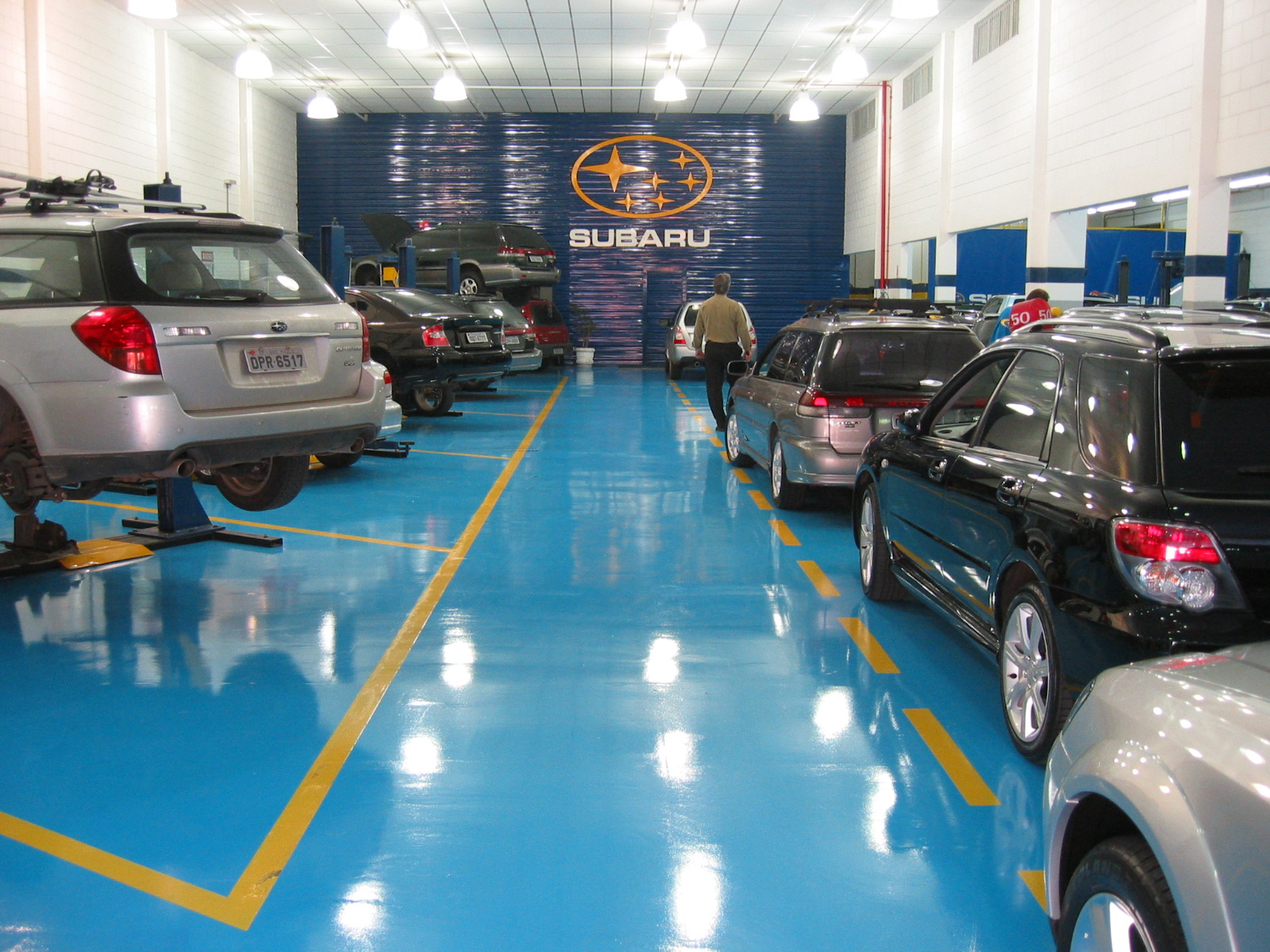 Galpão de concessionária com piso epóxi cinza e veículos estacionados para revisão.