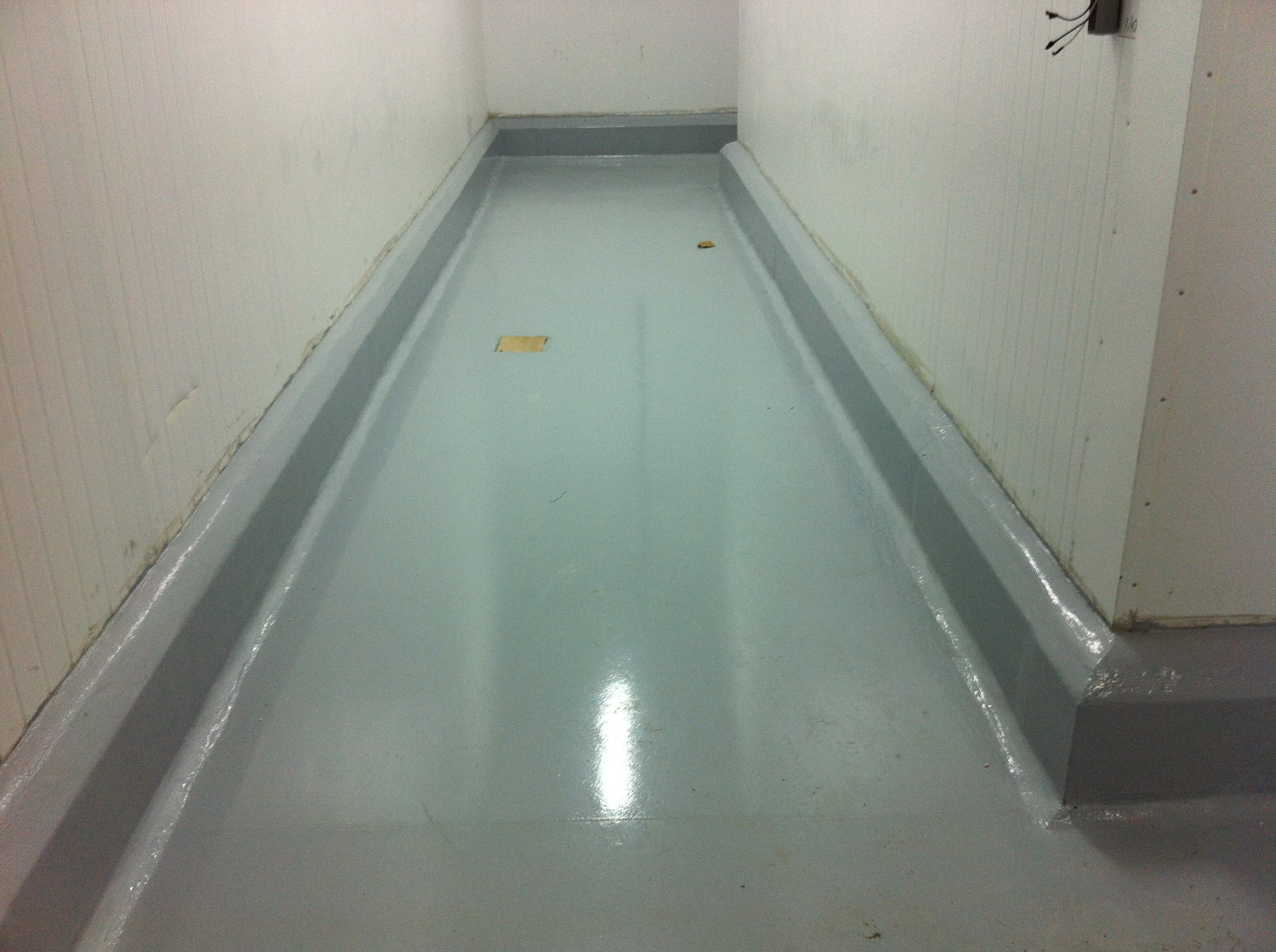 Detalhe de piso autonivelante branco em ambiente frigorificado, com acabamento resistente ao choque térmico.
