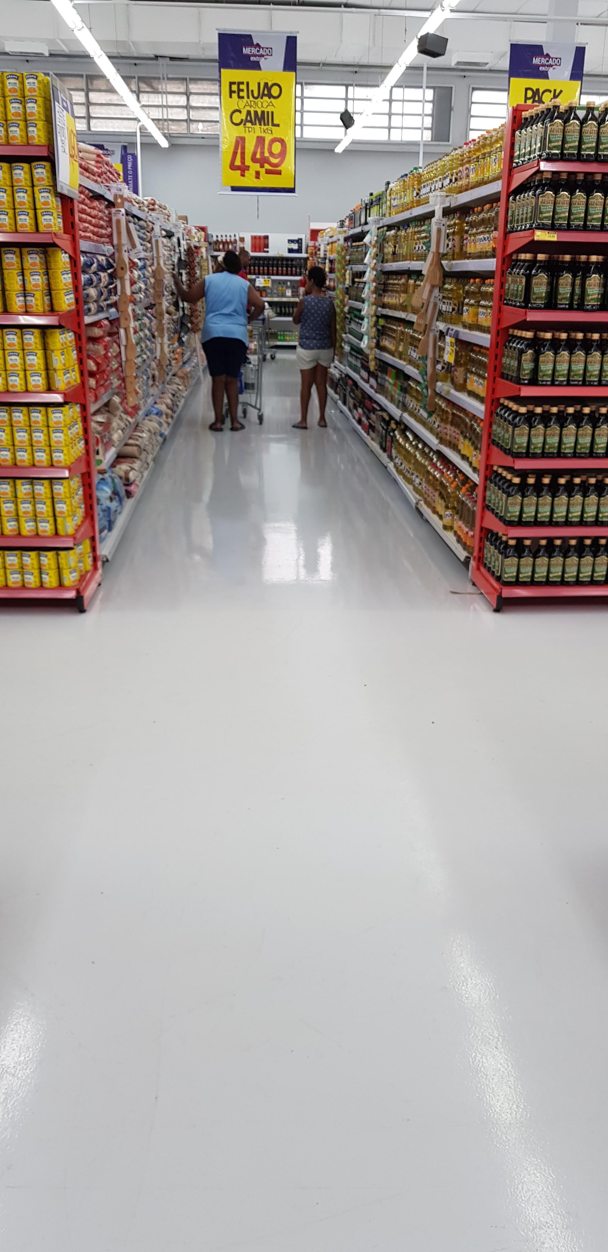 Área de vendas de supermercado com piso autonivelante claro, prateleiras e clientes circulando.