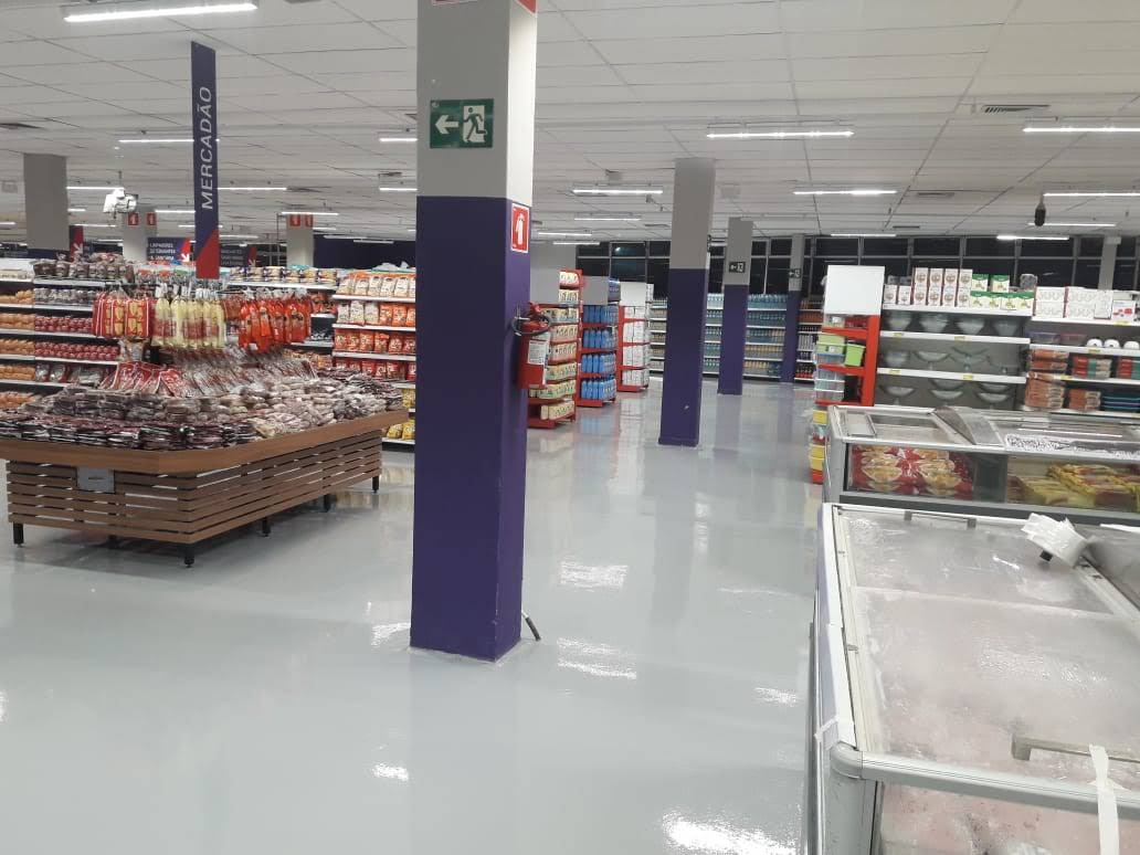 Setor de supermercado com piso autonivelante claro e prateleiras de produtos organizadas.
