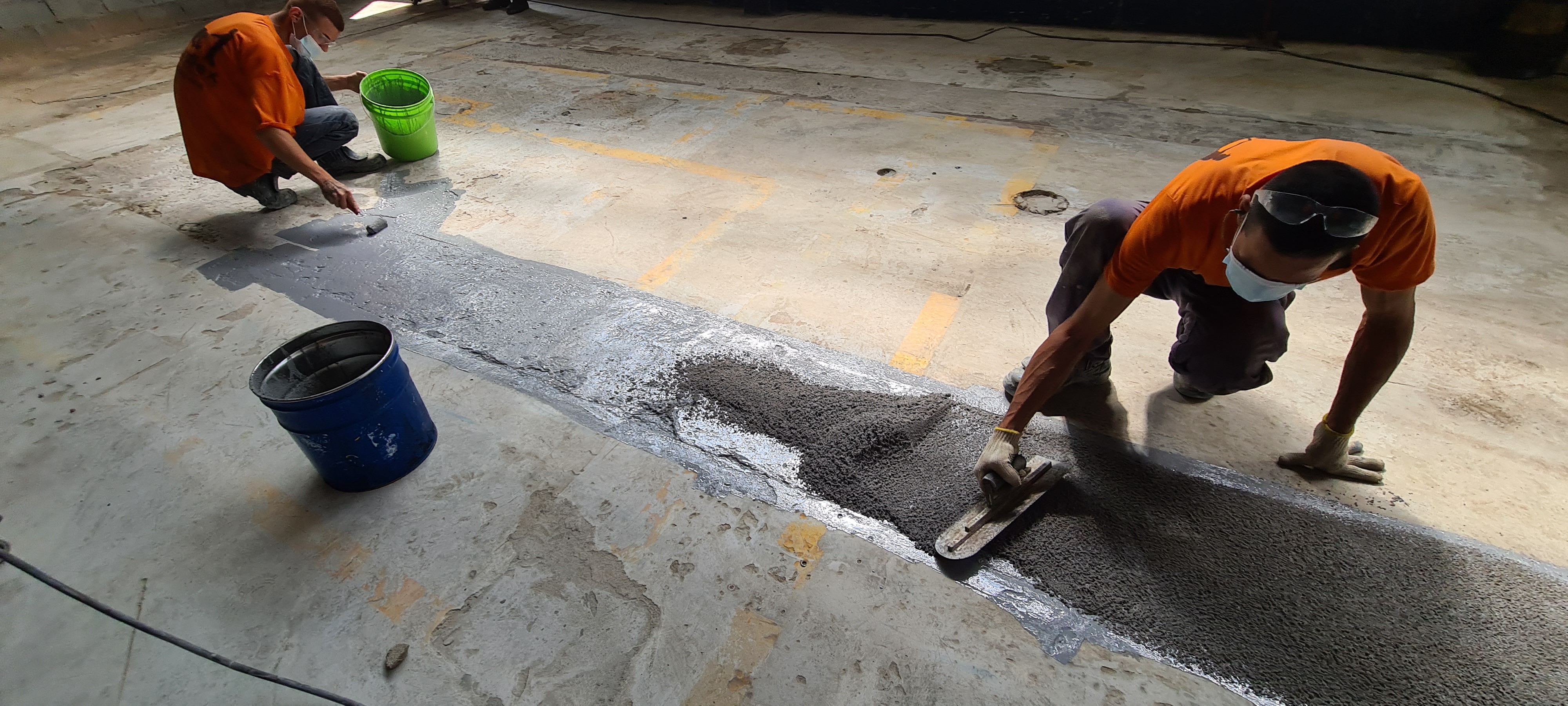 Close do reparo com argamassa epóxi finalizado, textura granulada cinza contrastando com o concreto original.