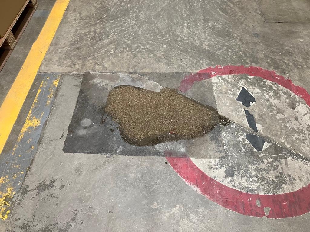 Remendo de piso industrial em concreto sobre sinalização circular vermelha, aguardando acabamento.