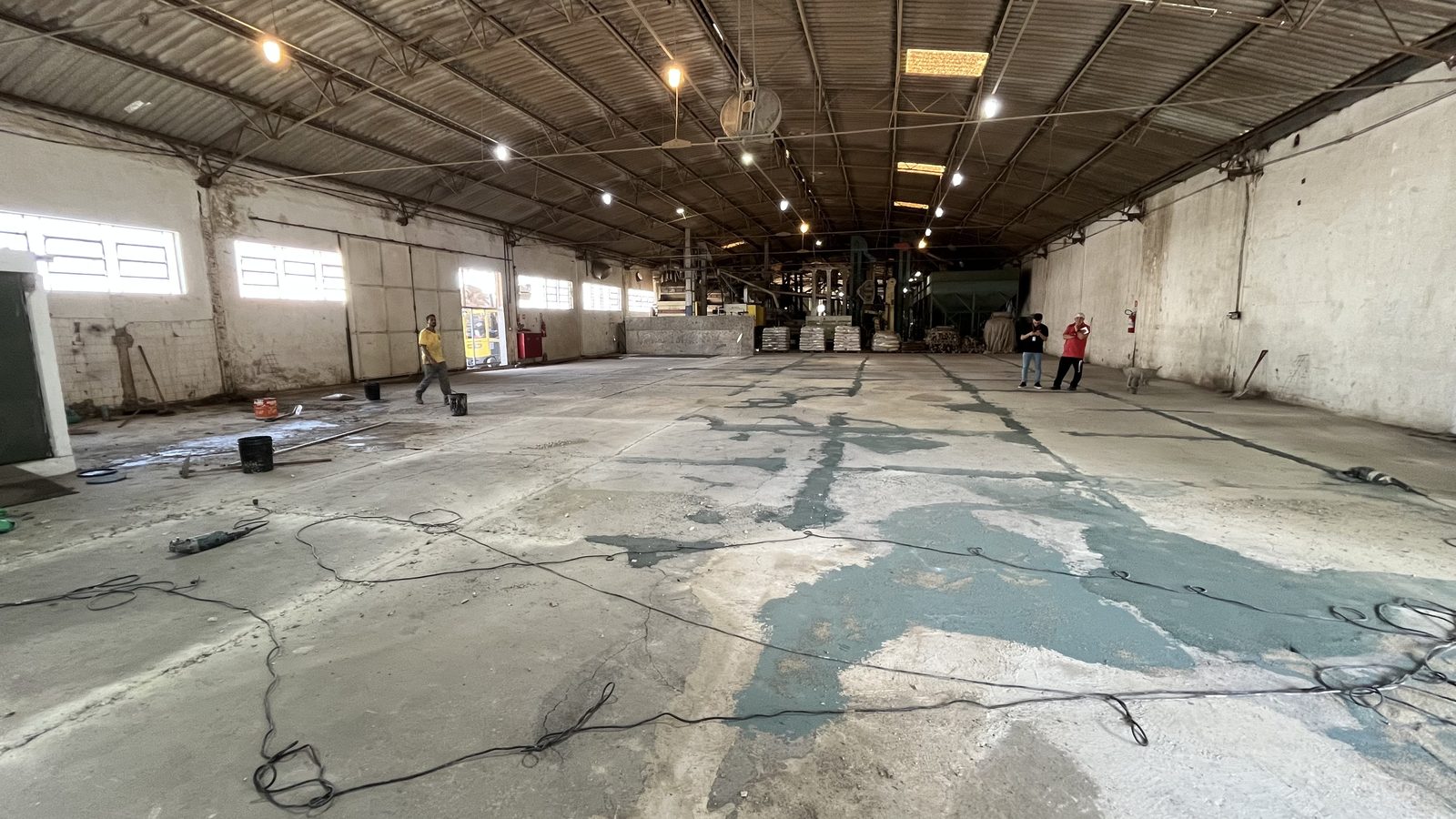 Galpão industrial com piso de concreto em preparação para manutenção, após remoção do revestimento antigo.