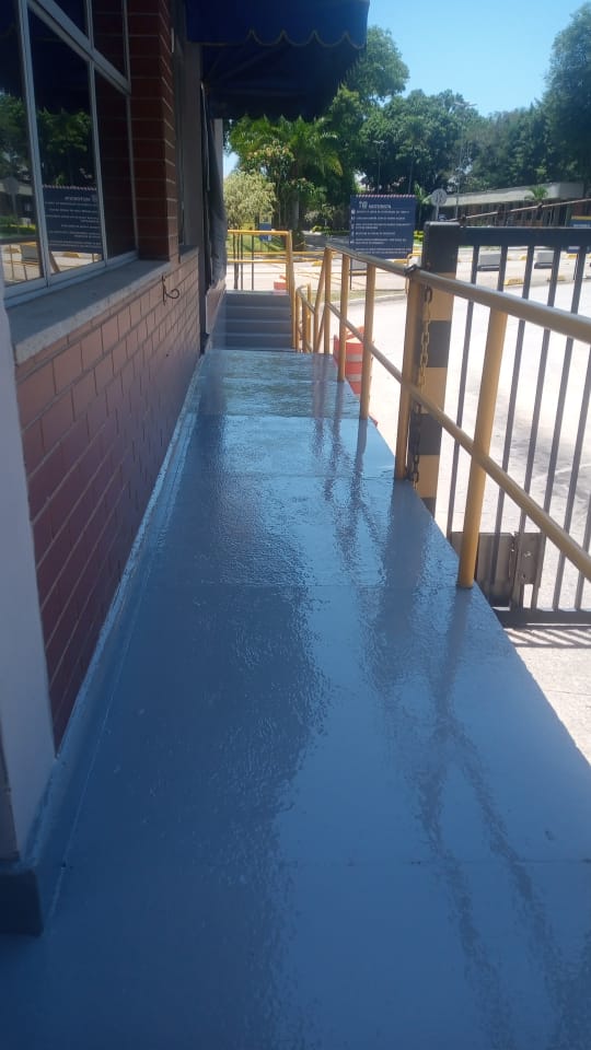 Detalhe de piso em poliuretano azul-claro texturizado, aplicado sobre rampa de acesso externa.