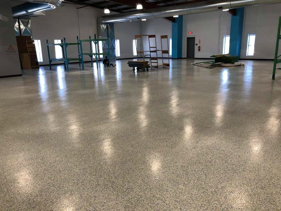 Salão comercial amplo com piso epóxi decorativo tipo flakes em tons de cinza e acabamento de alto brilho.