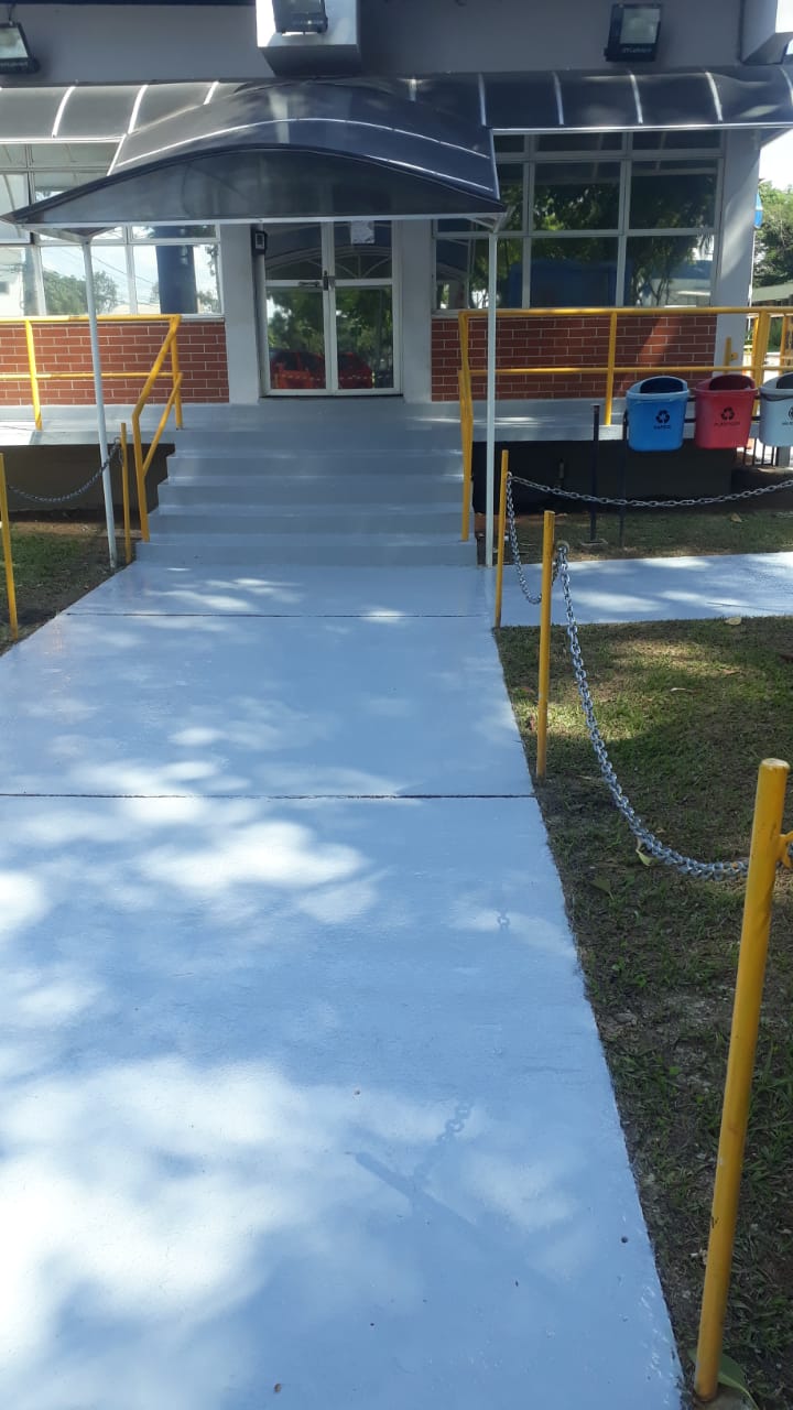 Escada e rampa de acesso institucional revestidas com piso em uretano azul-claro, corrimãos amarelos de segurança.