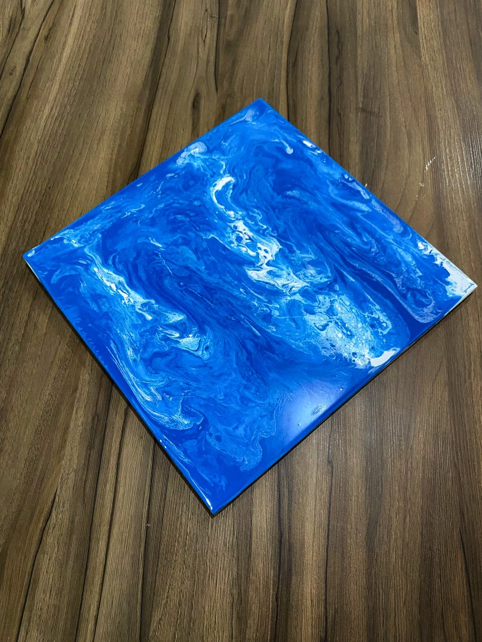 Amostra de piso epóxi 3D azul com efeito de ondas sobre bancada de madeira.