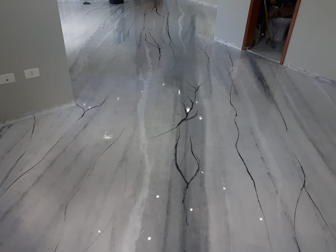 Piso epóxi 3D com efeito mármore cinza e veios escuros aplicado em ambiente residencial.