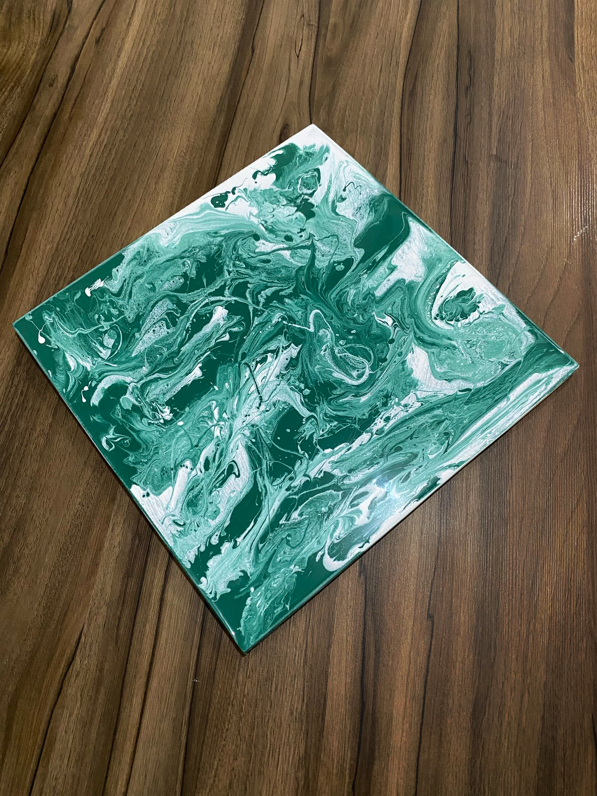 Amostra de piso epóxi 3D em tons de verde e branco marmorizados, mostrando o efeito de profundidade em close-up.