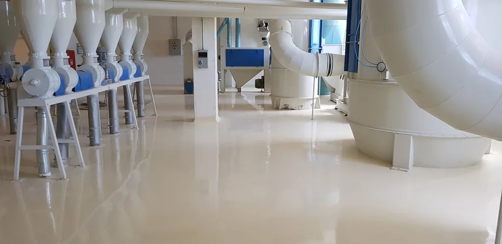 Área de moagem com piso autonivelante branco brilhante e equipamentos de processo em inox.