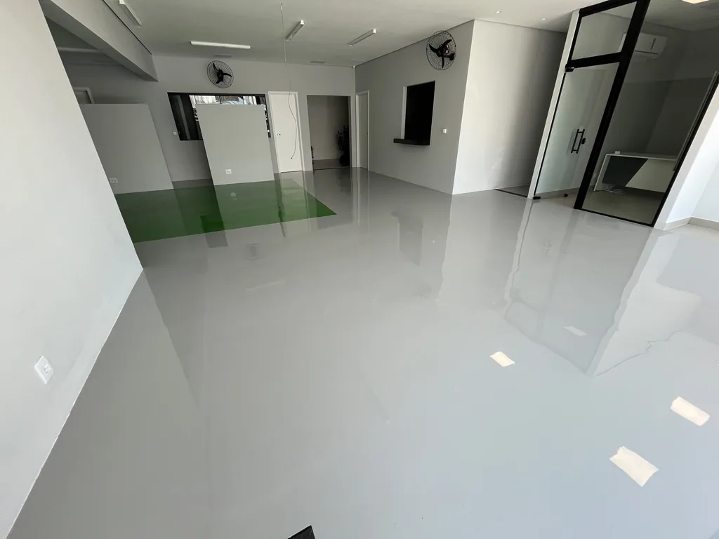 Sala comercial vazia com piso autonivelante cinza claro brilhante e detalhe verde no piso.