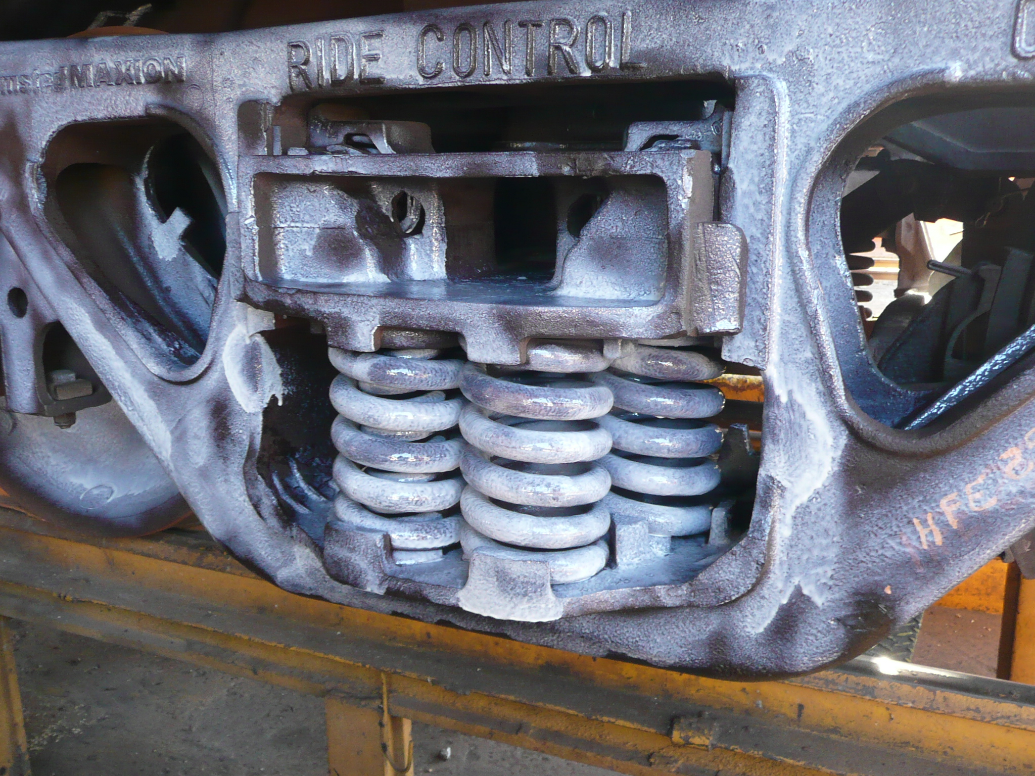 Detalhe de peça metálica de suspensão ferroviária já revestida com conversor de ferrugem, acabamento uniforme sobre superfície antes oxidada.